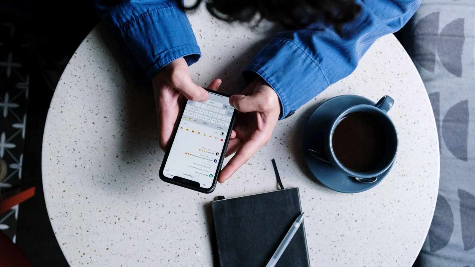 Customer checking a product on a smartphone beside a notebook and coffee