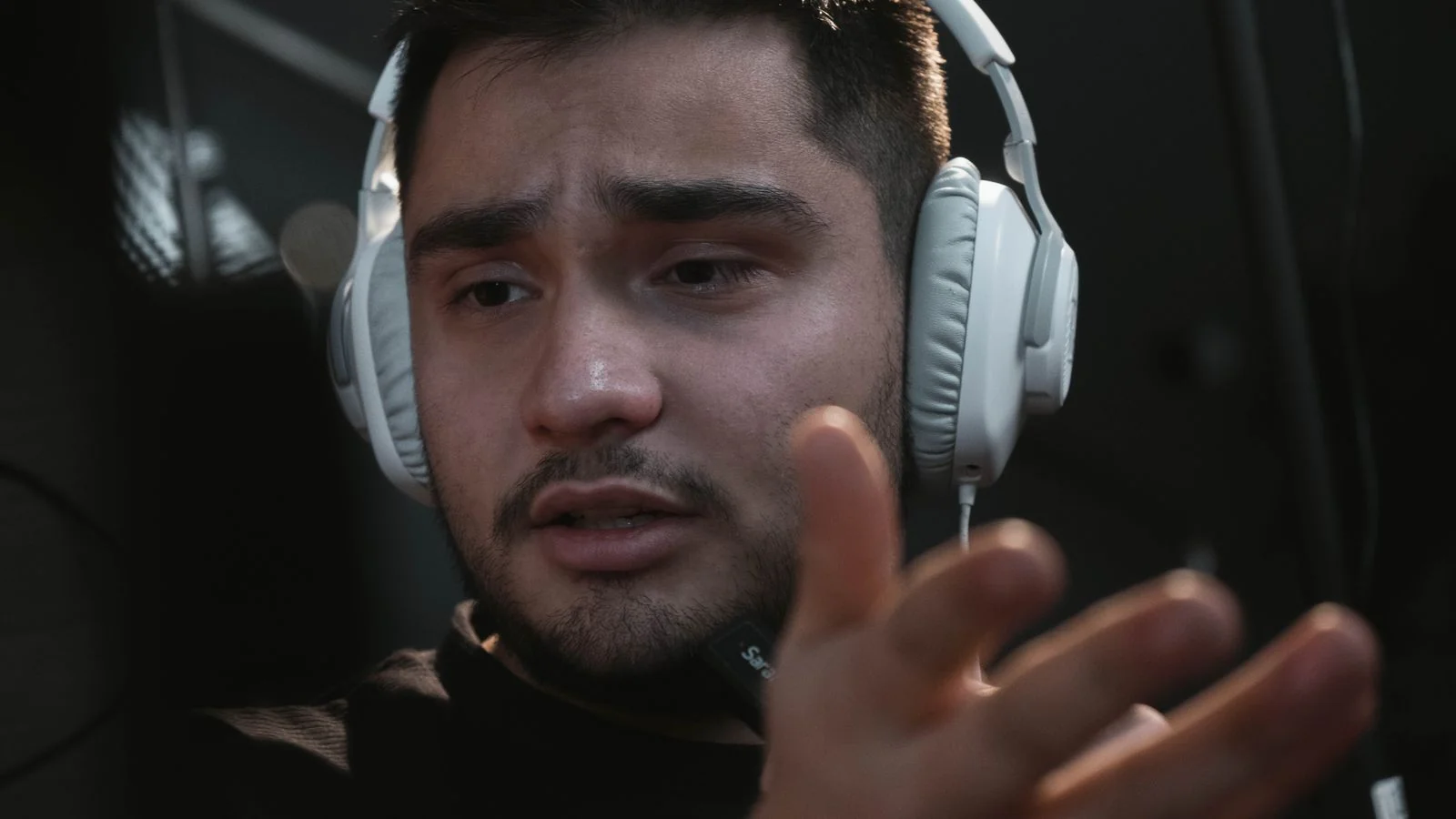 A host wearing headphones leaning into a studio microphone, the seat a good pitch earns you