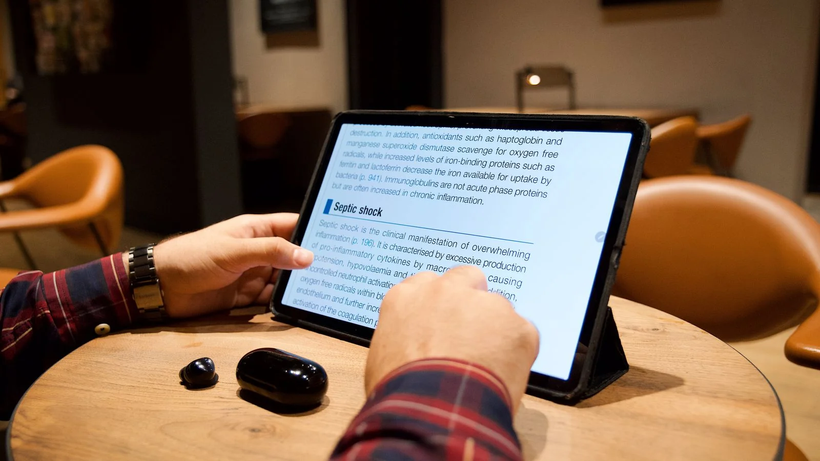A man reading a news article on a tablet in a cafe, the timely, retrievable content that wins citations on ChatGPT's browsing surface