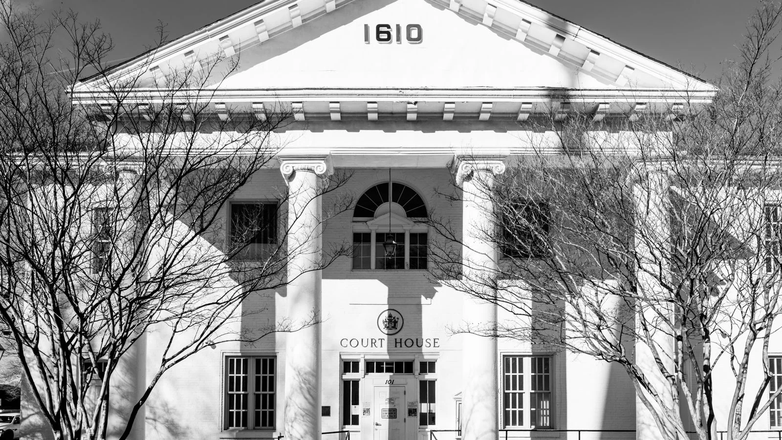 A black-and-white view of a historic courthouse facade with classic columns