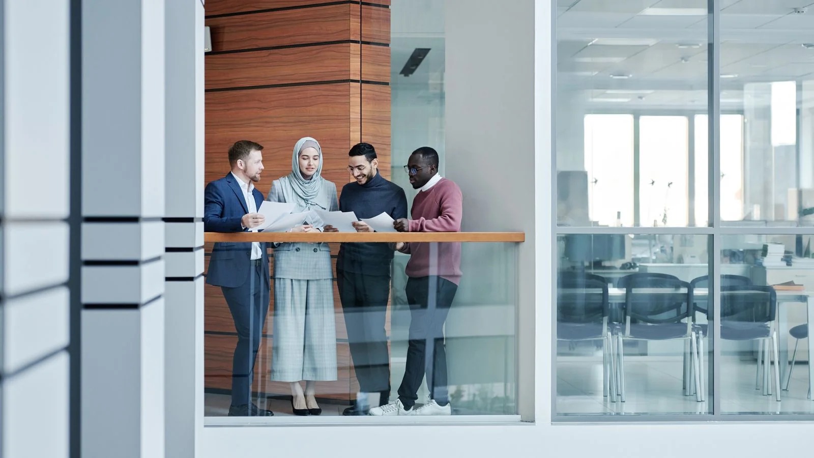 Diverse colleagues collaborating in a glass-walled office, the current employees who refresh a review page