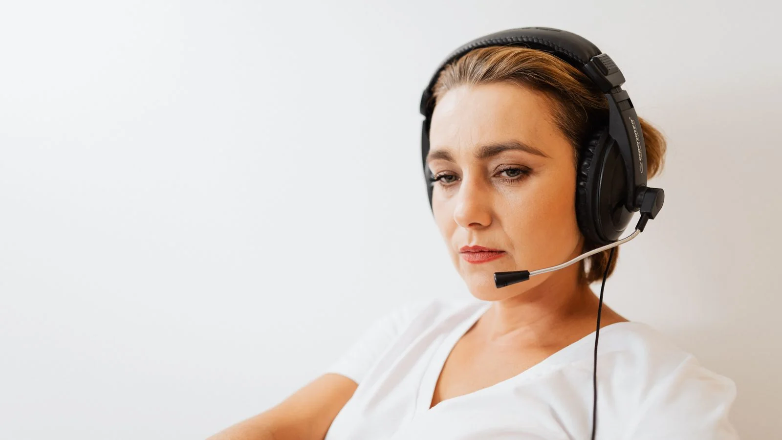 Customer support agent wearing a headset and concentrating at her workstation, the calm processing step before any reply gets written