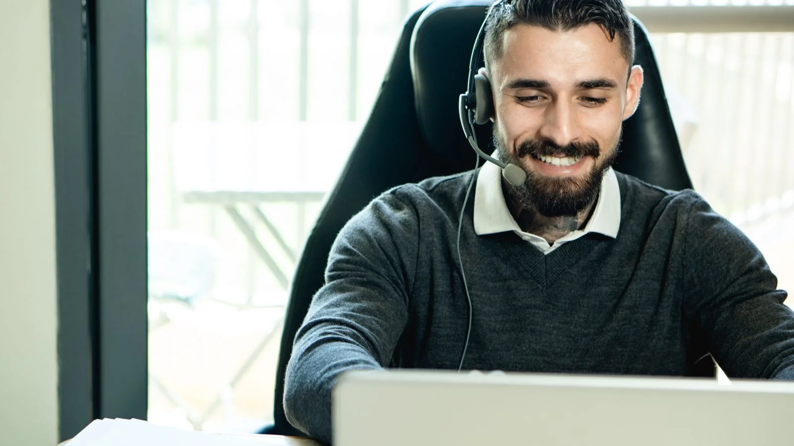 Support specialist wearing a headset at a desk, the calm posture a good review reply should project