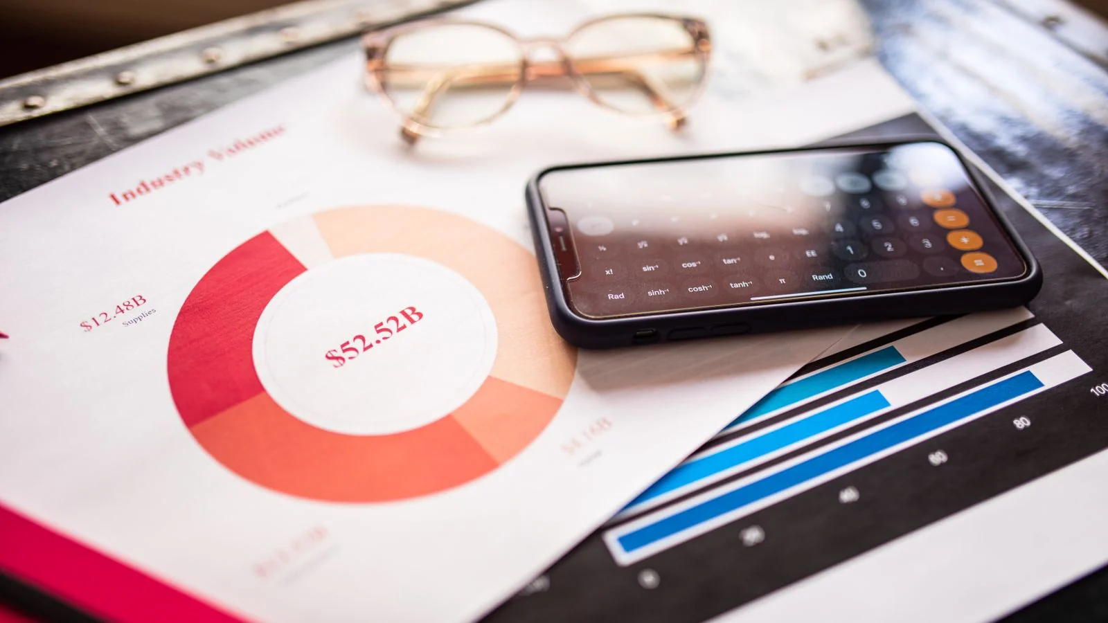A smartphone resting on printed charts and analytics reports on a desk