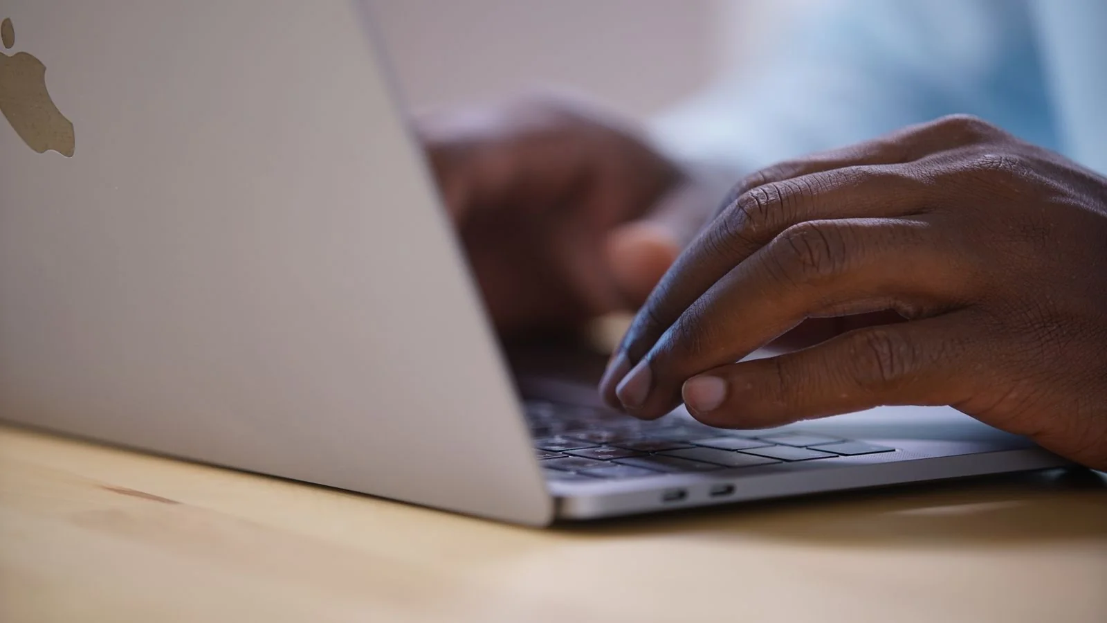 Hands typing on a laptop keyboard, the everyday work that gets a page indexed so Gemini's grounded mode can find it