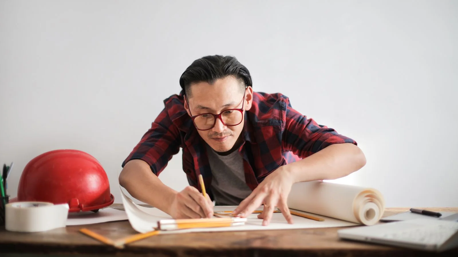 Young engineer in glasses sketching a draft by hand at a table, working out the structure before building anything