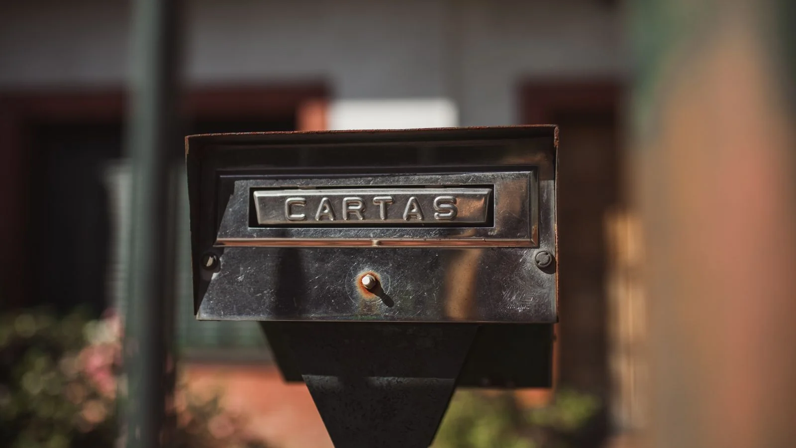 Close-up of a weathered outdoor mailbox labeled Cartas catching afternoon sunlight