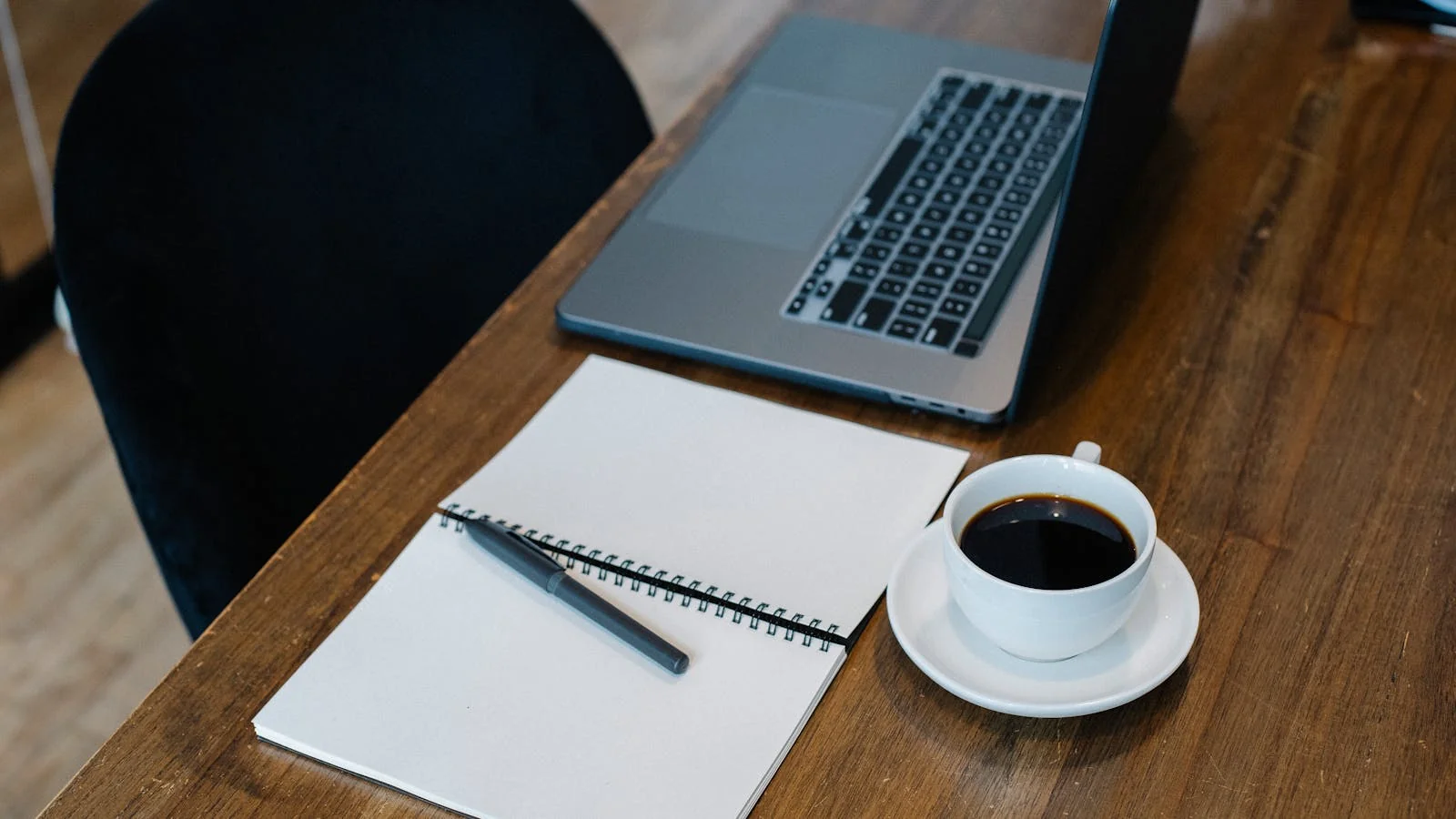 A warm minimalist desk with an open laptop, a notebook, and a coffee cup, the kind of pre-work morning where PR teams convince themselves Friday will work fine