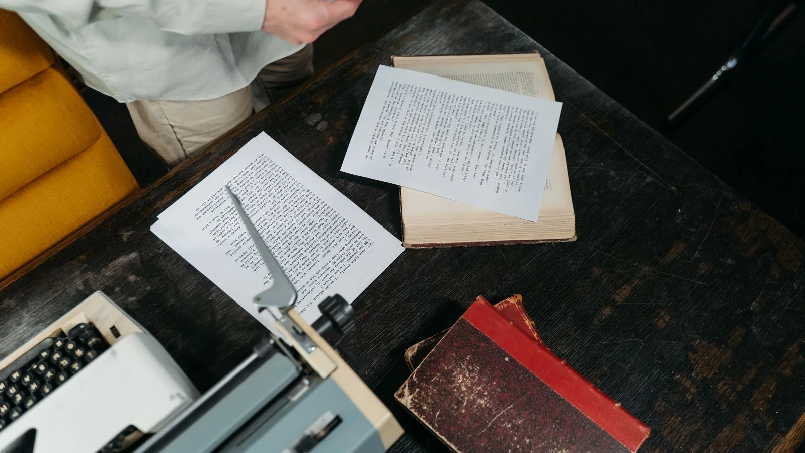 Overhead view of a wooden desk holding a typewriter, loose papers, and old books, the workspace where boilerplate was born