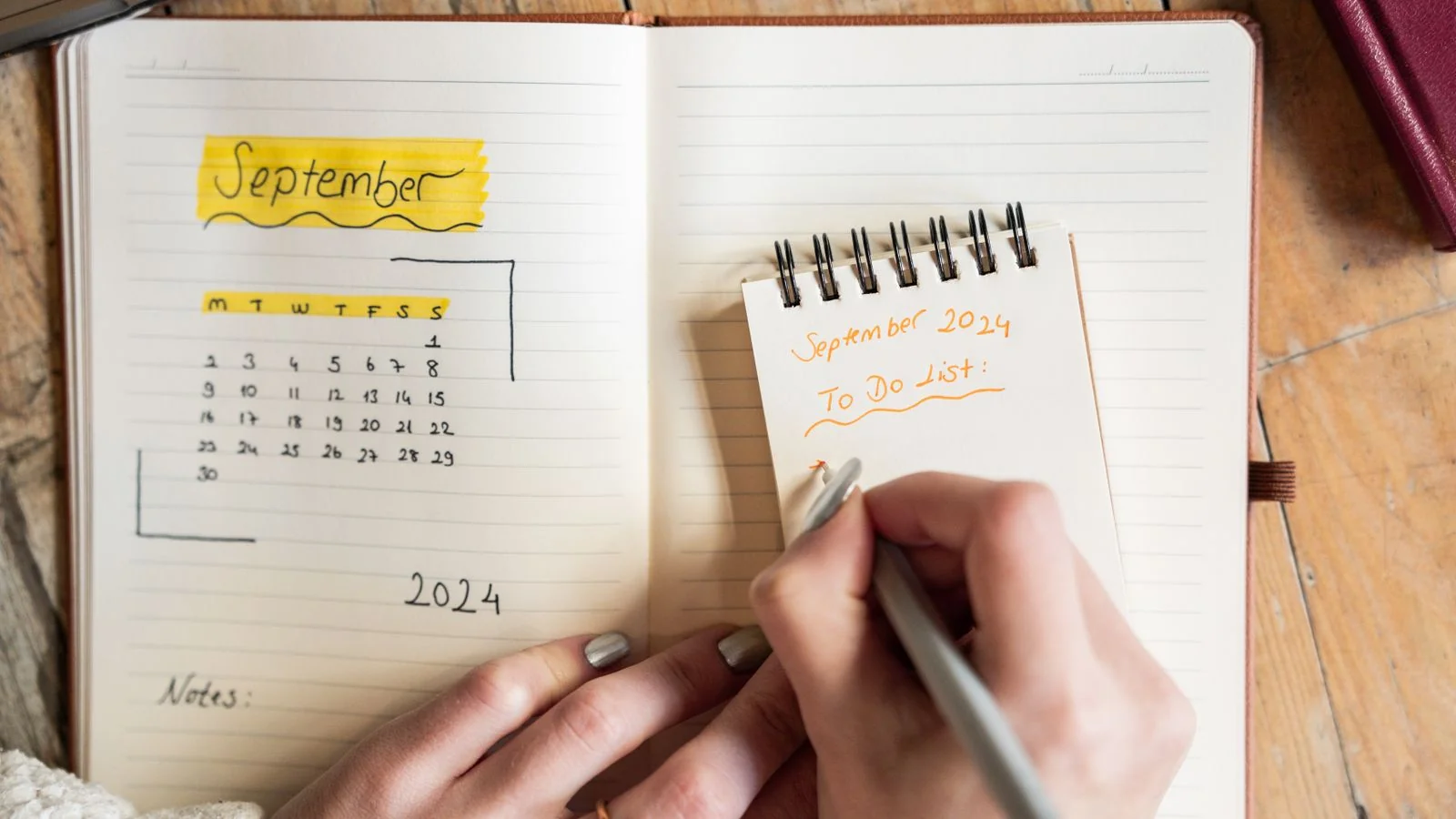 Hands writing in an open weekly planner