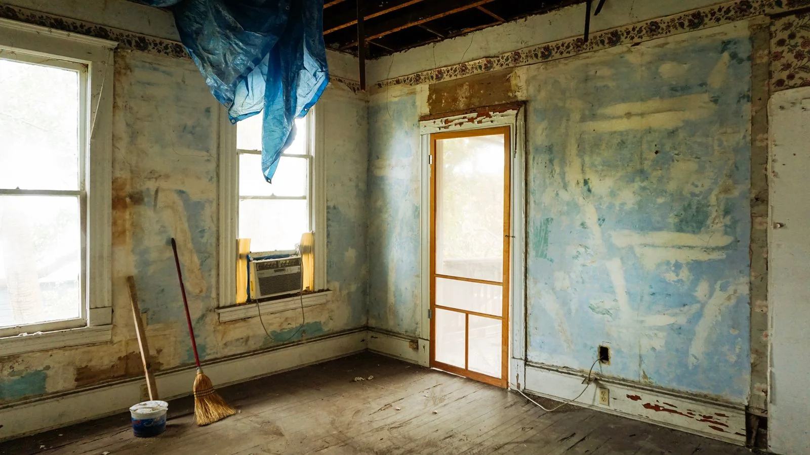 Empty room mid-demolition with peeling walls and tools, the before photo readers cannot look away from.