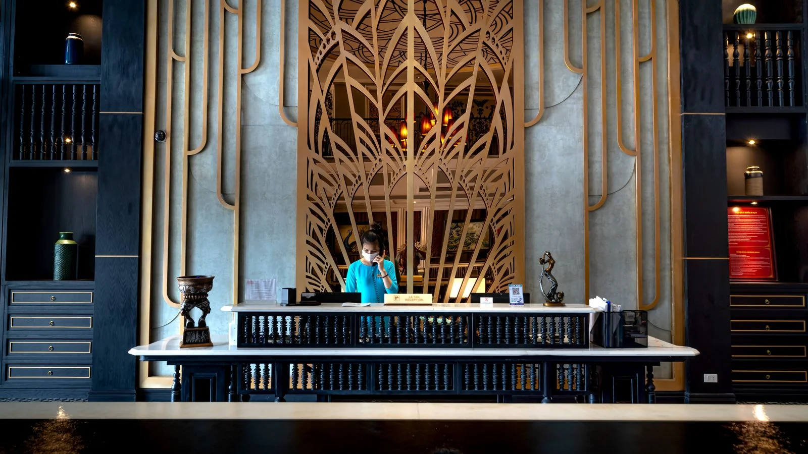 A hotel reception desk with a receptionist at work, the part of your property no editor will write about.