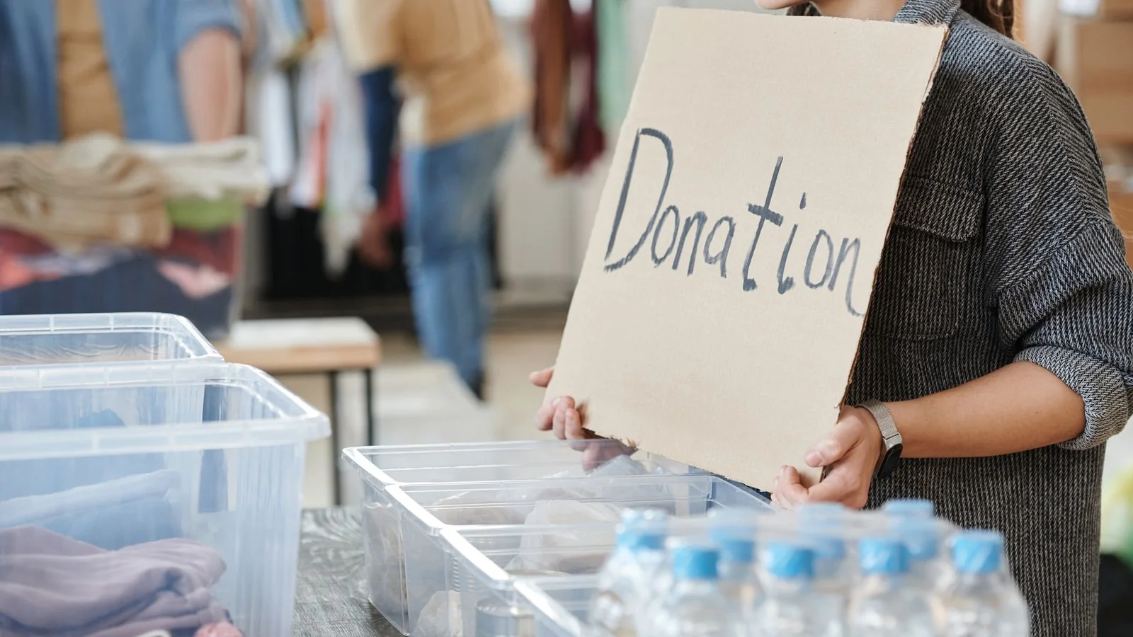 A volunteer holding a donation sign at a charity collection, the community angle that needs numbers behind it