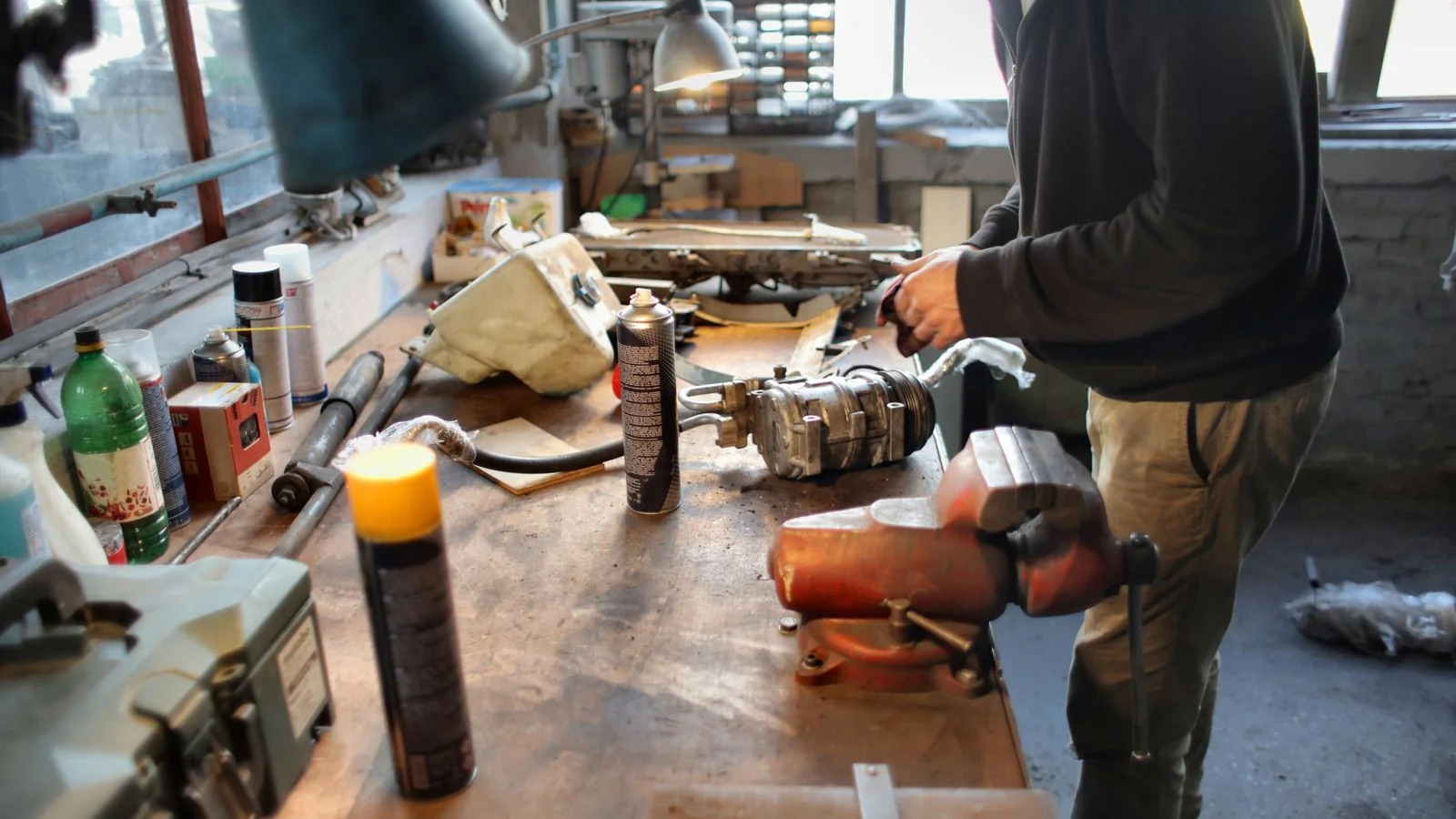 A mechanic repairing machinery with tools in a well-equipped workshop.