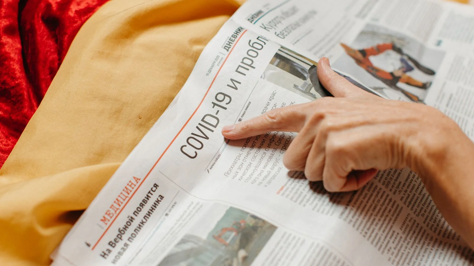 A hand pointing to a headline in a printed newspaper, the news peg every release needs.