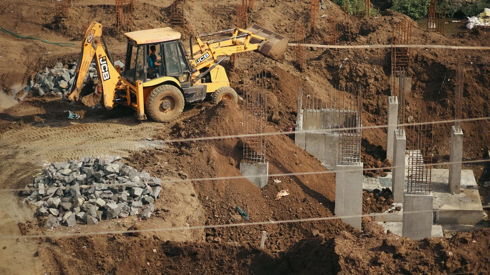 An excavator moving soil at a work site, the ground-level reality of septic system repair and replacement.