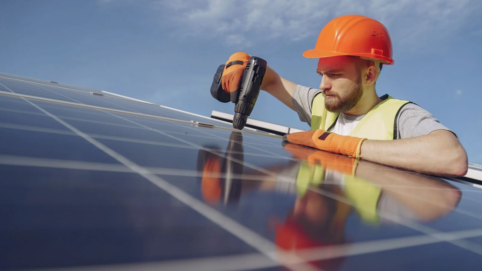 Worker installing a solar panel on a residential roof
