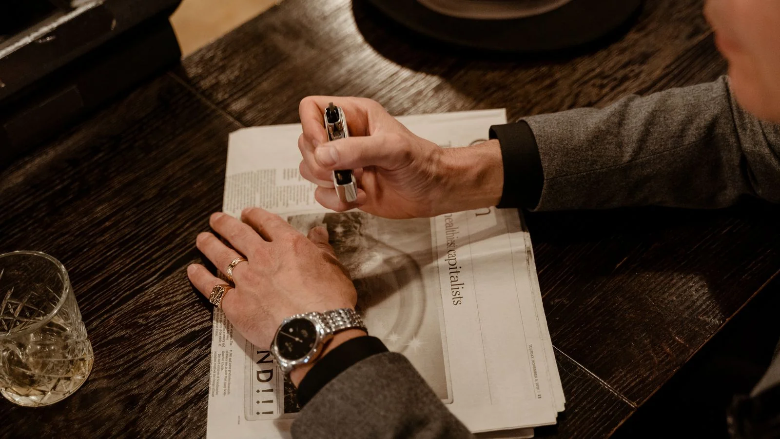 Man in a suit reading a newspaper at a desk with a pen in hand, the ten-second triage every studio pitch has to survive
