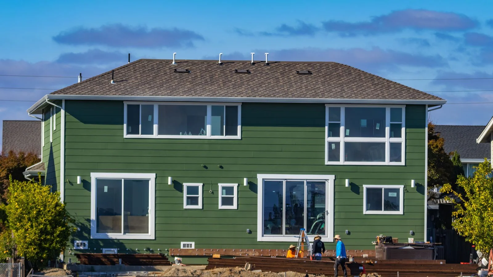 A modern house under construction with new windows and a crew working outside.