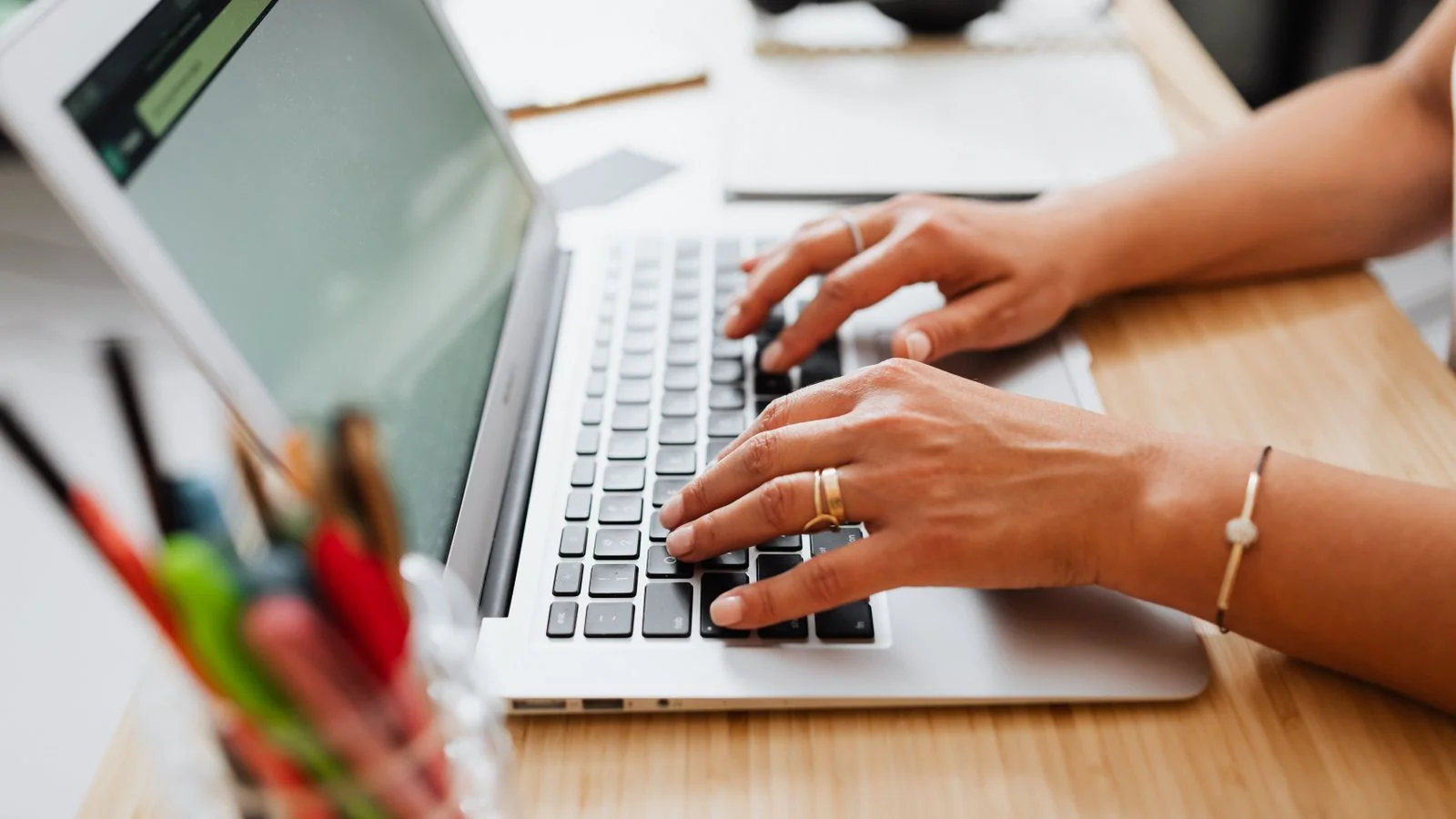 A person typing on a laptop at a wooden desk, the unglamorous work that real About-page proof points come from