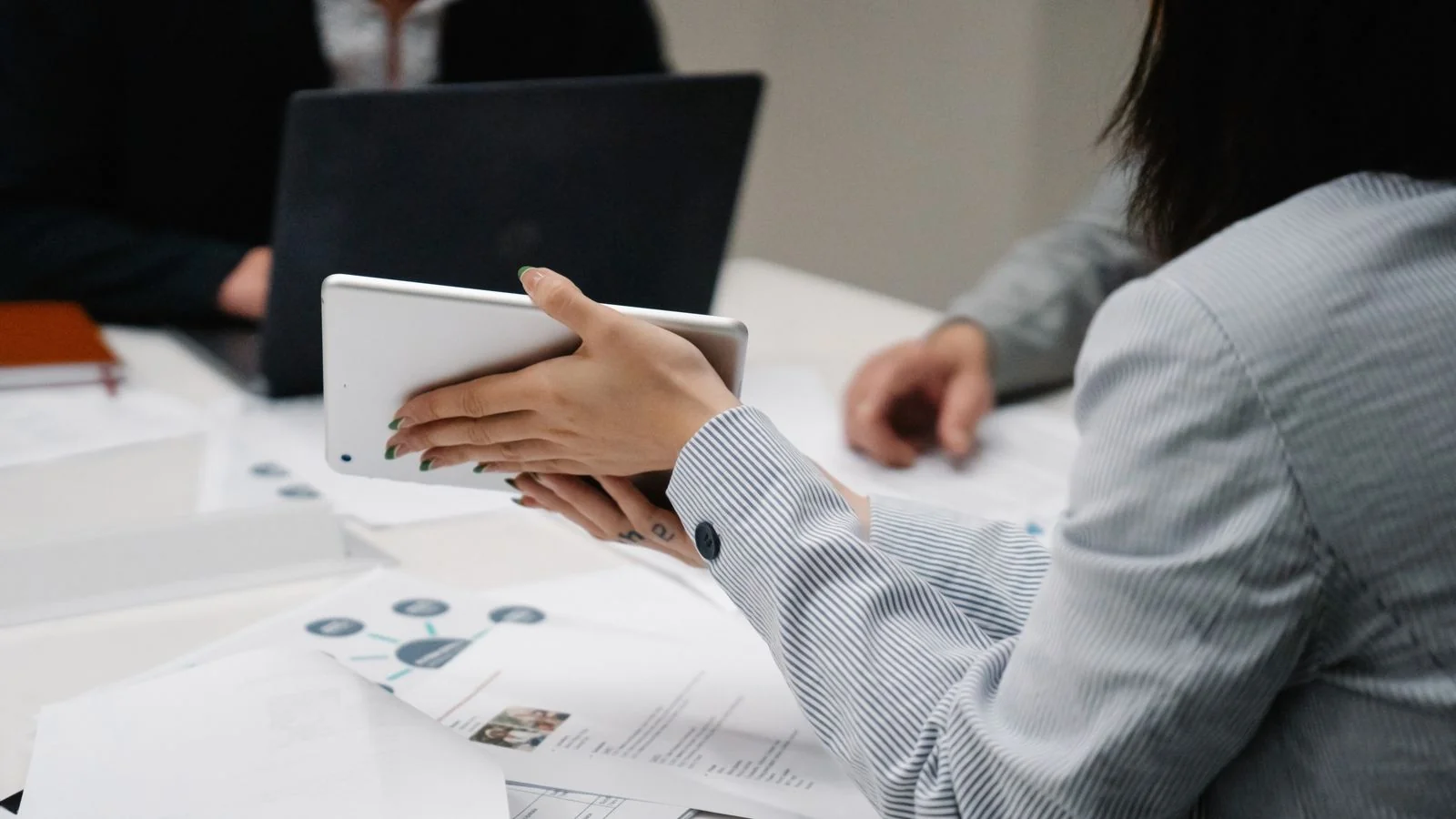 Business team meeting around a table with a tablet and printed documents