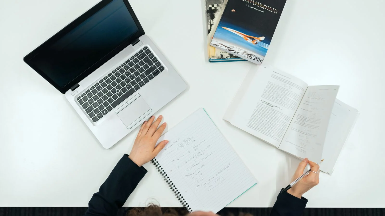 A desk with a laptop, books and notes, the preparation a technical pitch needs
