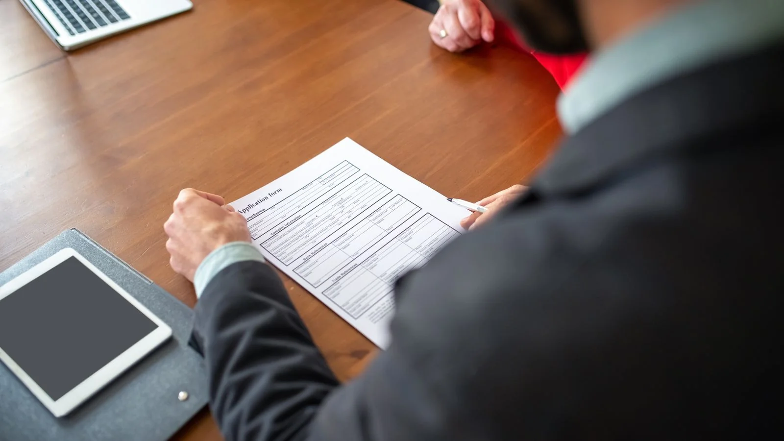 Two professionals reviewing an application form across a desk, the monthly screening every candidate passes through