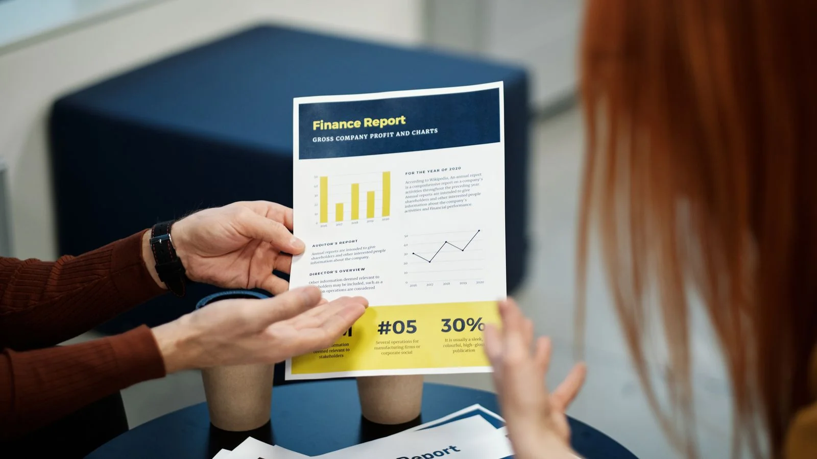 Two colleagues reviewing a printed financial report together in an office