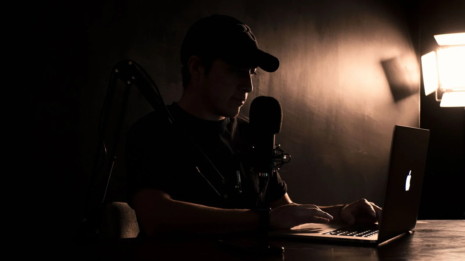 A creator working on a laptop with a microphone setup, adapting to a publication's distinct voice and format