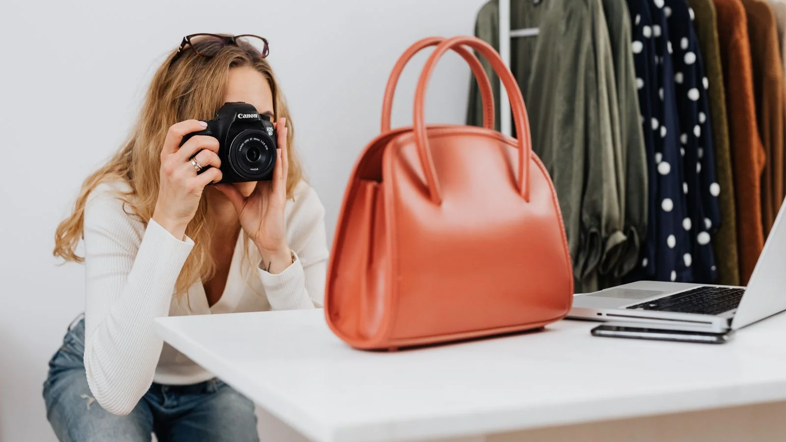 A woman photographing a handbag for an online store, matching copy to the exact item the buyer sees