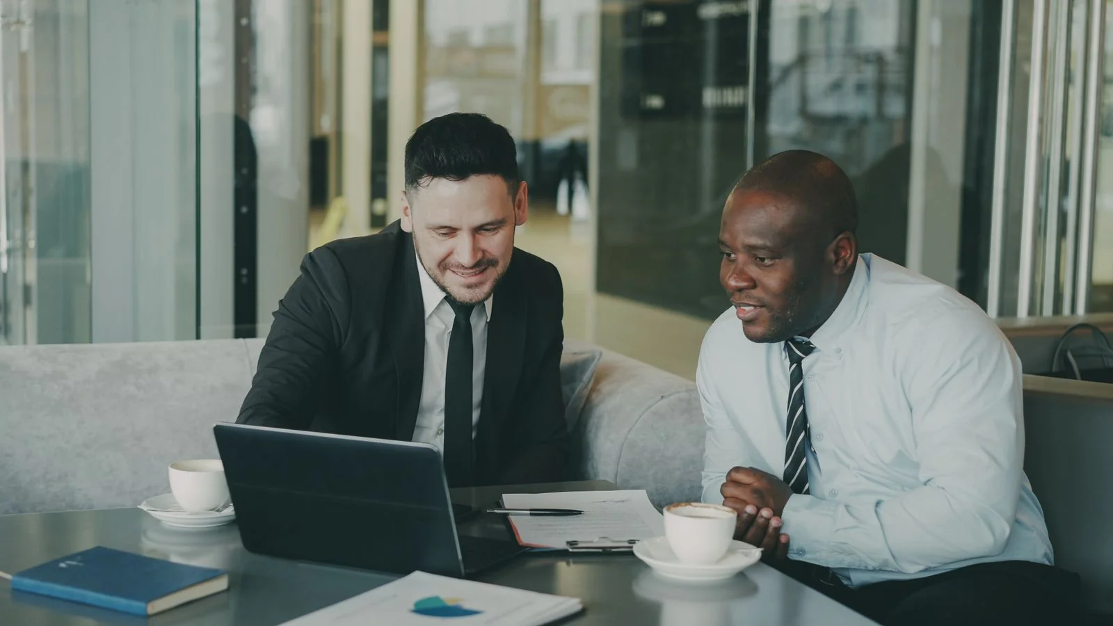 Two professionals reviewing work on a laptop together, the outreach that turns contributors into promoters