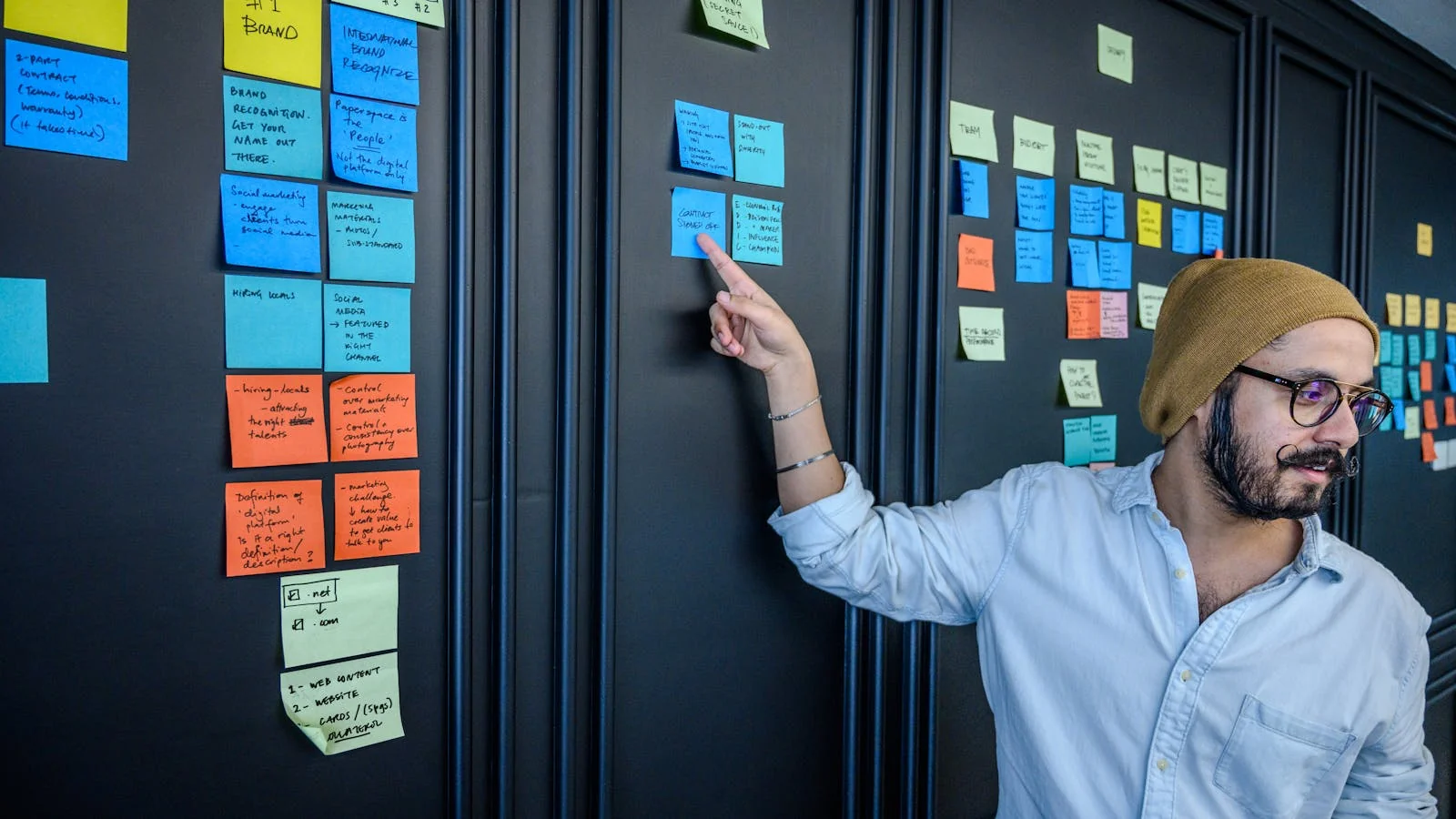 A founder pointing at sticky notes during a strategy session, working out a point worth arguing
