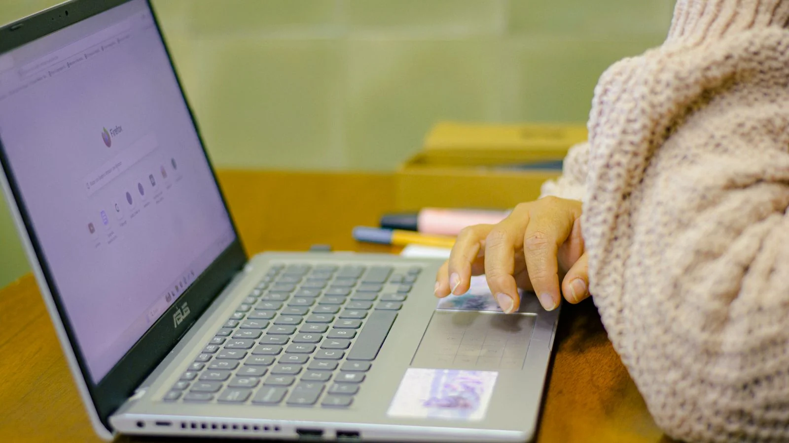 Student working on a laptop at a wooden desk, reviewing credit submissions online