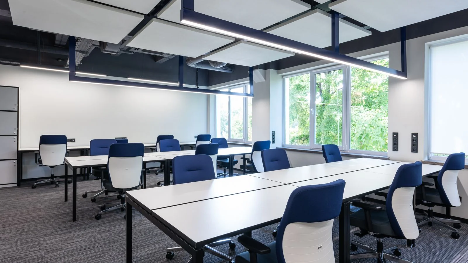 Rows of empty white desks and blue chairs in an open office, echoing shrinking newsrooms