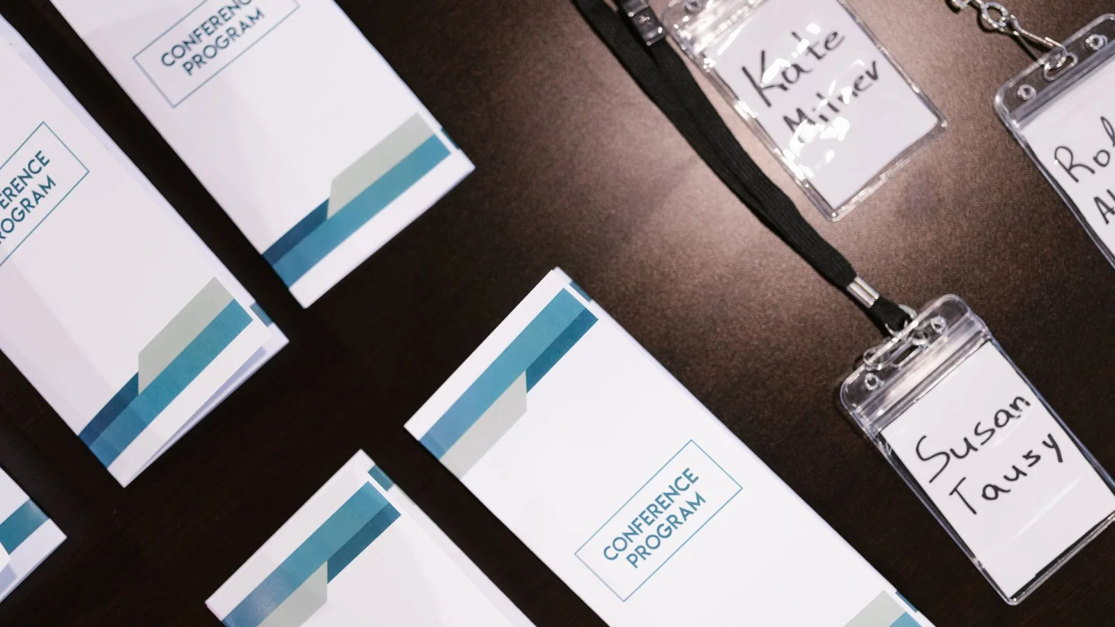 Conference programs and name badges laid out on a table, many names, one event