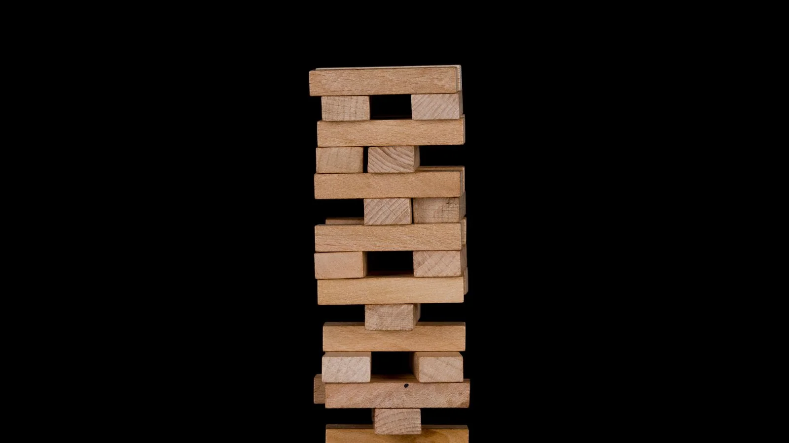 Wooden stacking blocks piled into a tower against a black background