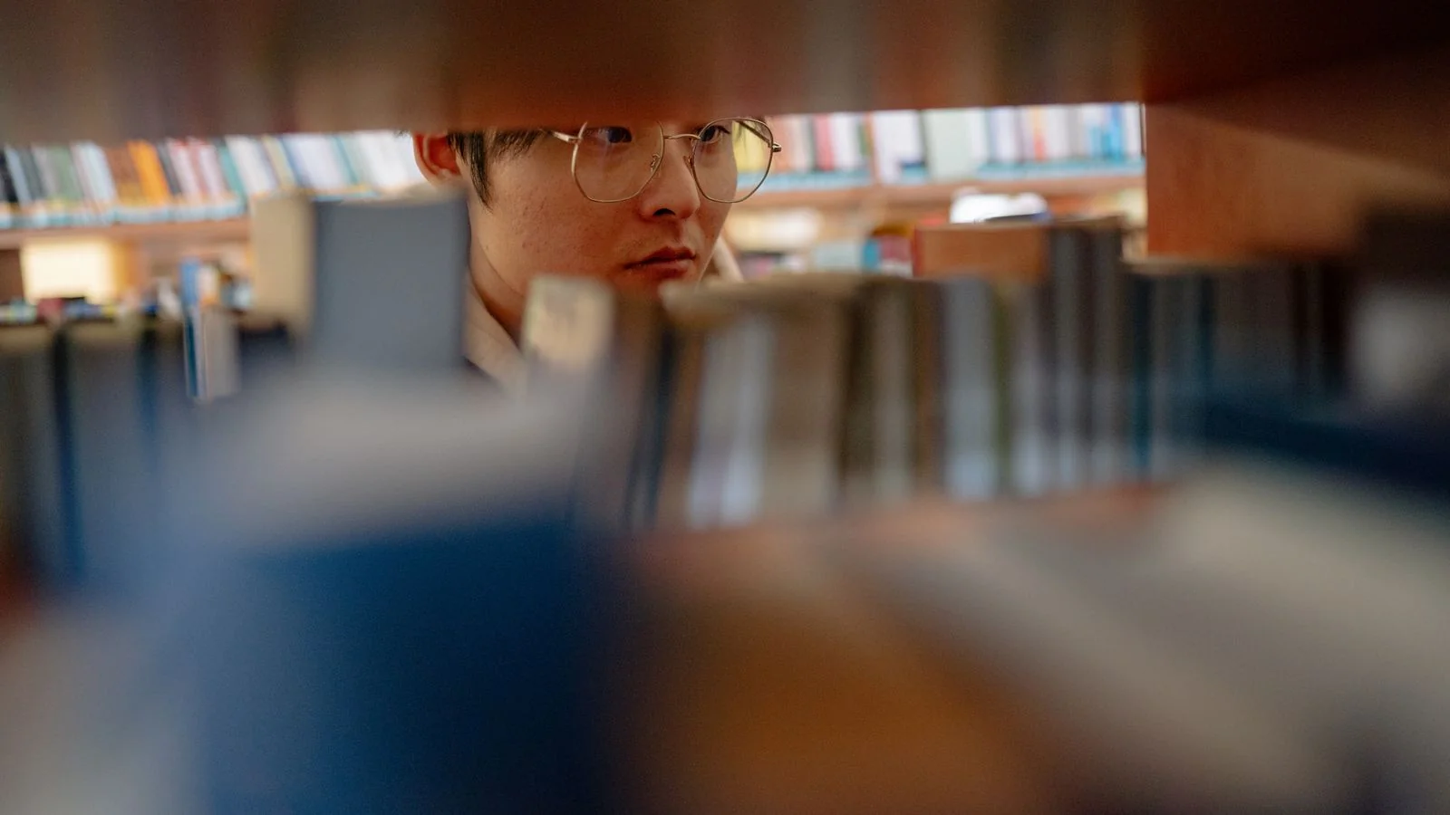 Young man studying between library shelves, a reminder that both features depend on sources