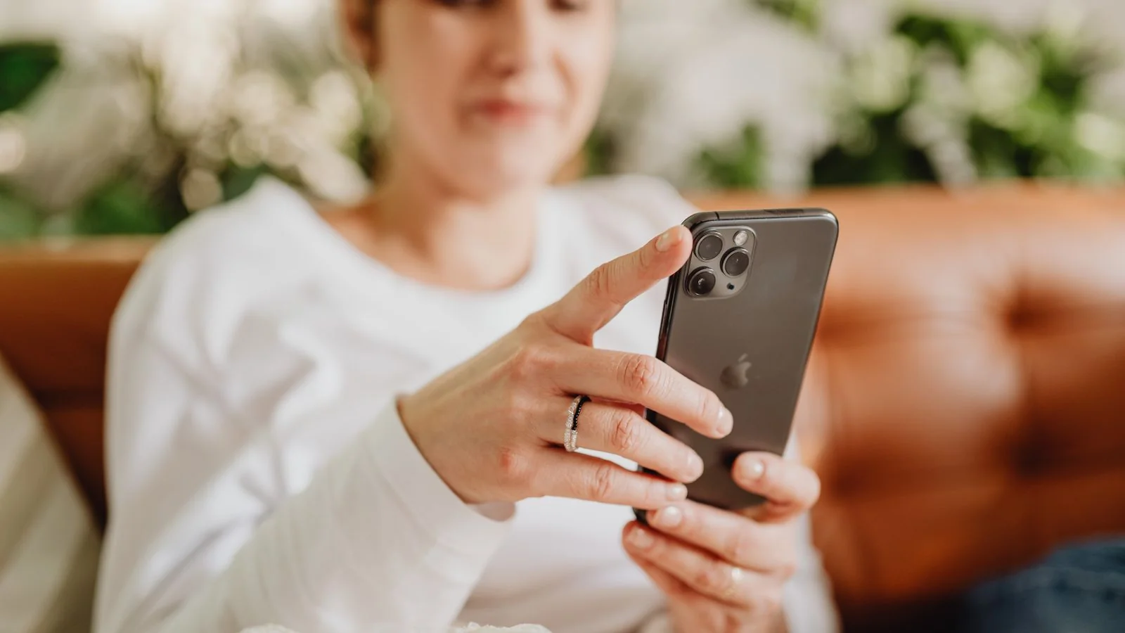 Woman on a couch checking her smartphone, verifying her identity to claim a Google knowledge panel