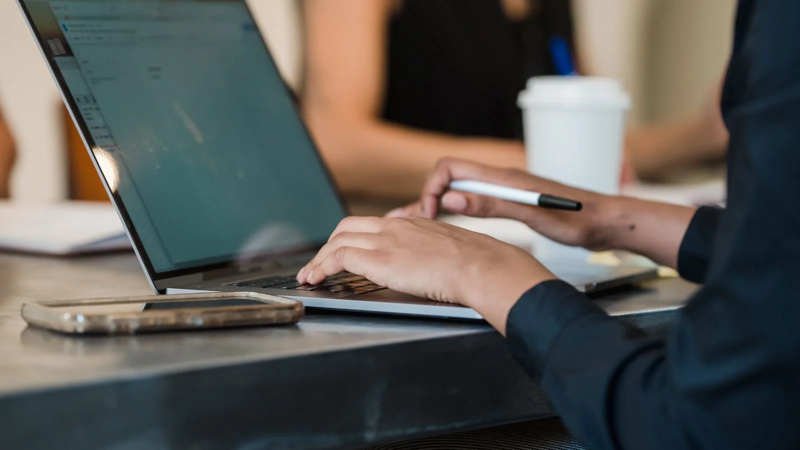 A professional typing on a laptop in a modern office, the daily work behind an authority that likes never measure