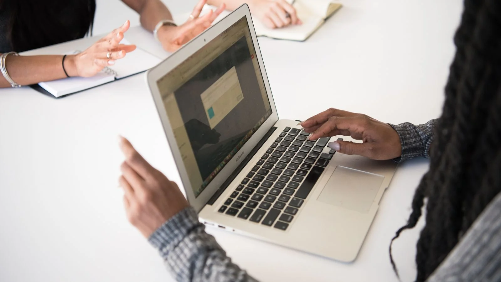 Colleagues collaborating around a laptop, the kind of professional network whose recognition turns into authority