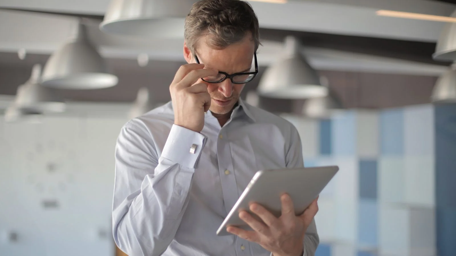 A man reading an article on a tablet in a cafe, attention that long-form has to keep earning line by line