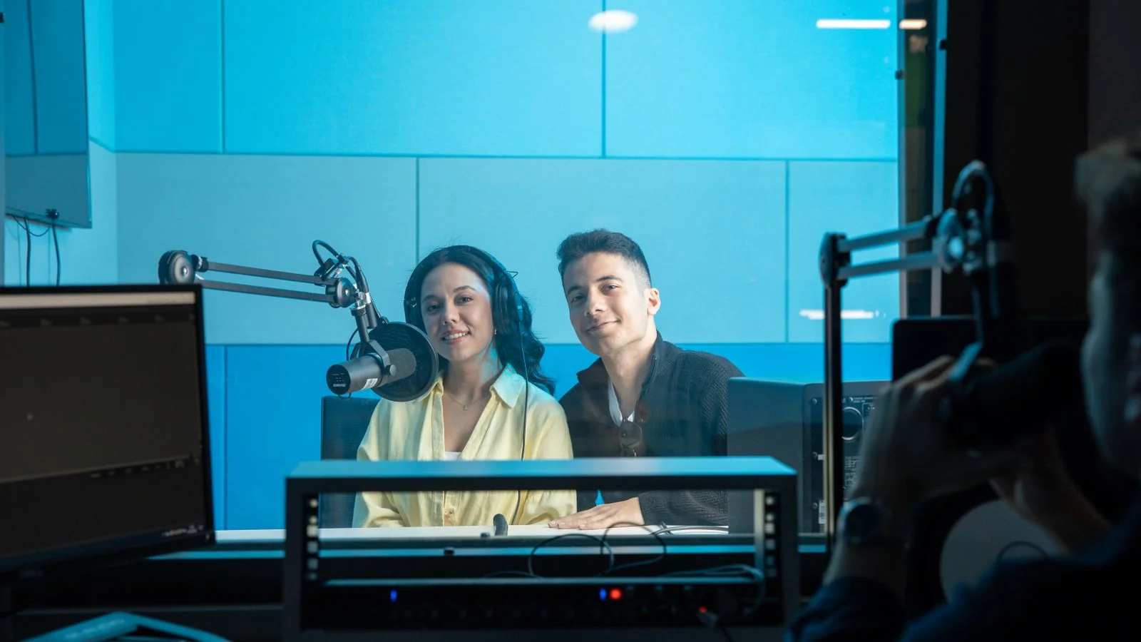 Two hosts speaking into microphones in a radio studio, a channel for earned coverage