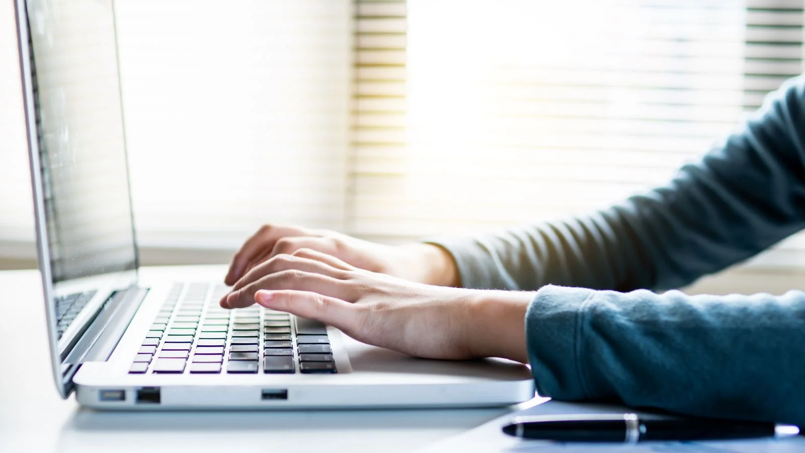A person typing on a laptop, the moment an embargo either holds until the lift time or breaks early