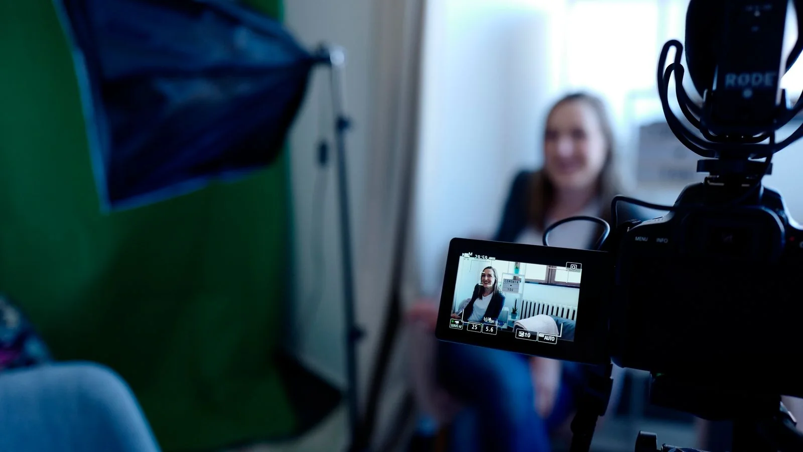 A woman is recorded in a professional studio with video and lighting equipment.