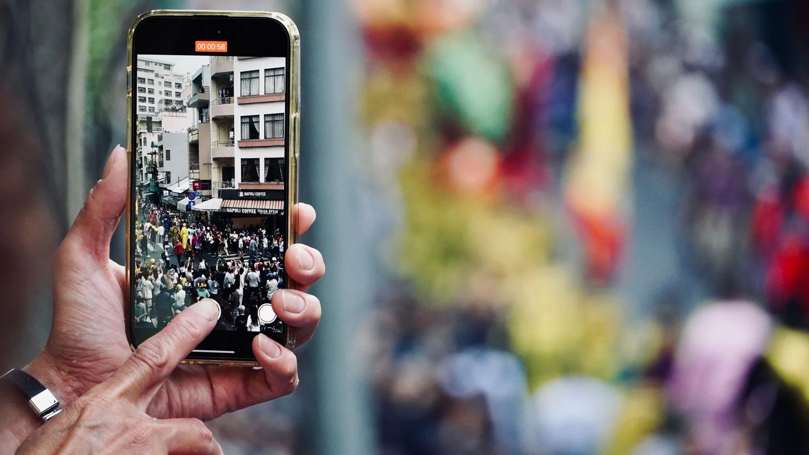 Street parade captured on a mobile phone screen, news increasingly consumed through social feeds