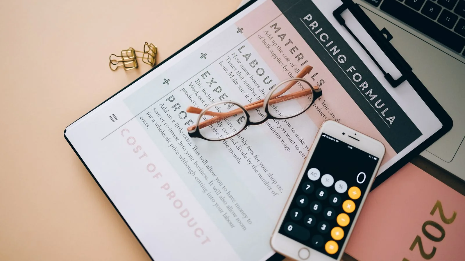 Overhead view of a calculator, a pricing formula document and eyeglasses on a desk, the arithmetic every PR budget needs