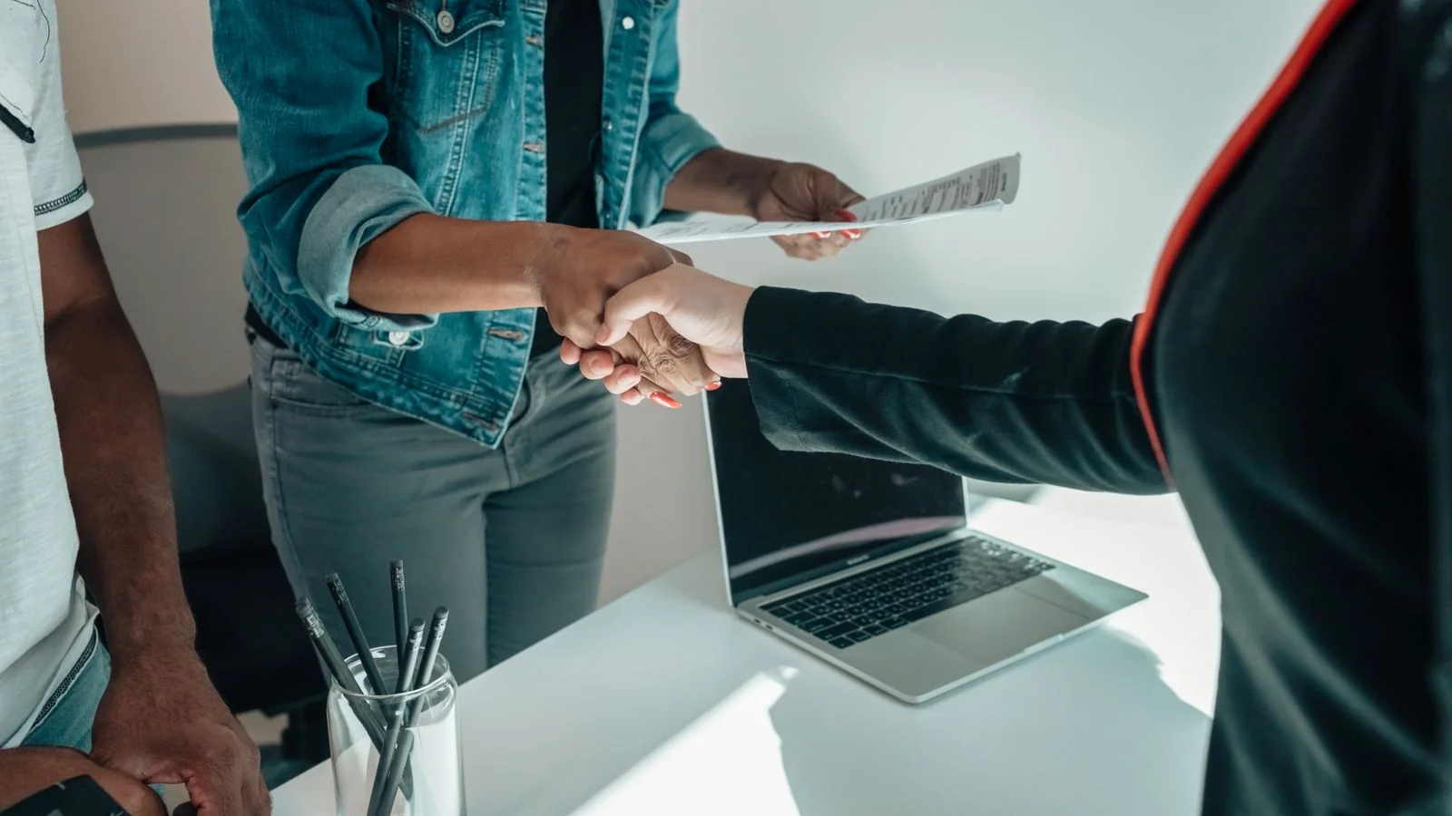 Two people shaking hands over a desk, the decision that often follows a private search of someone's name