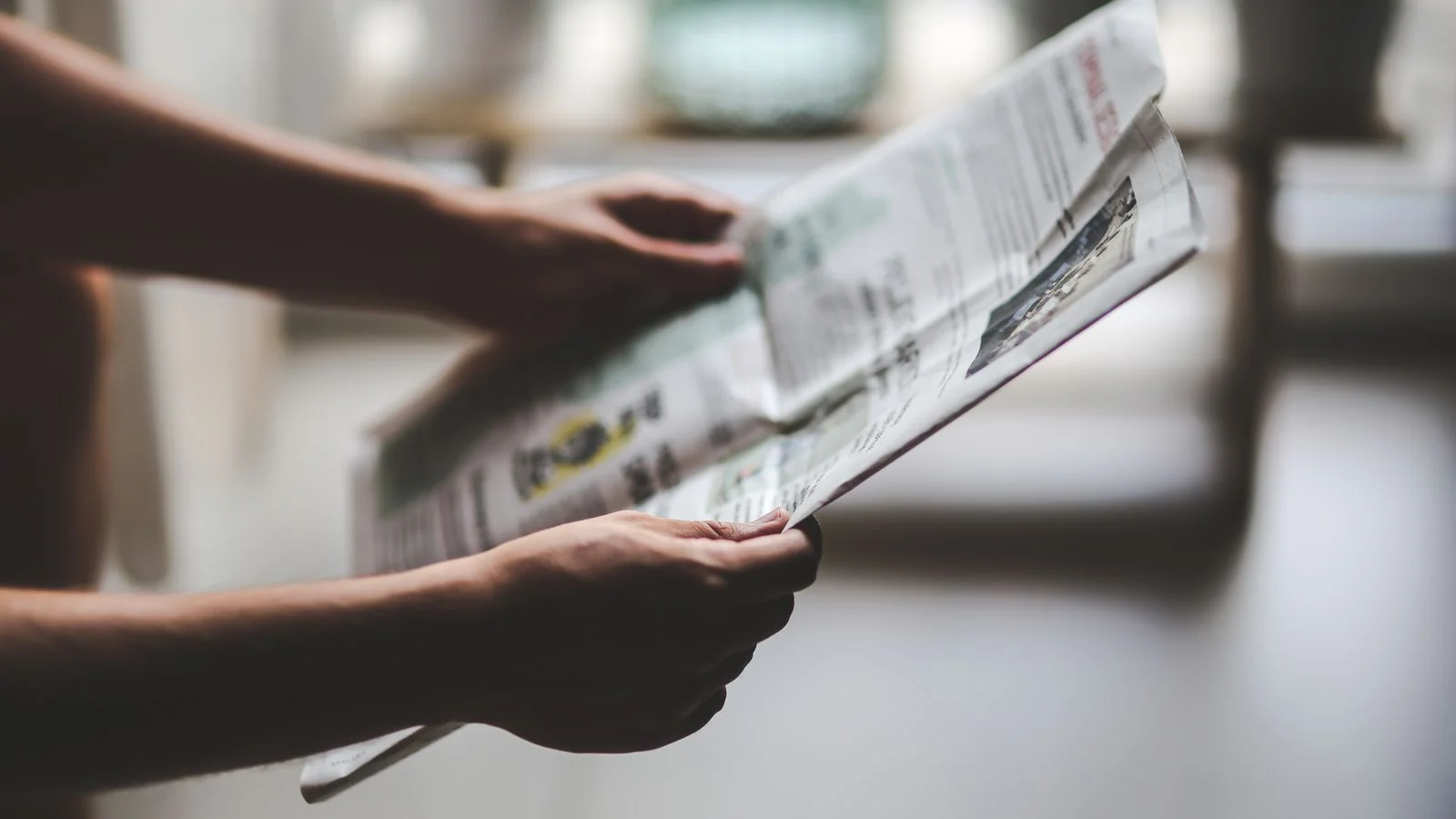 Hands holding a newspaper, the opinion section where op-eds sit apart from the paper's editorials