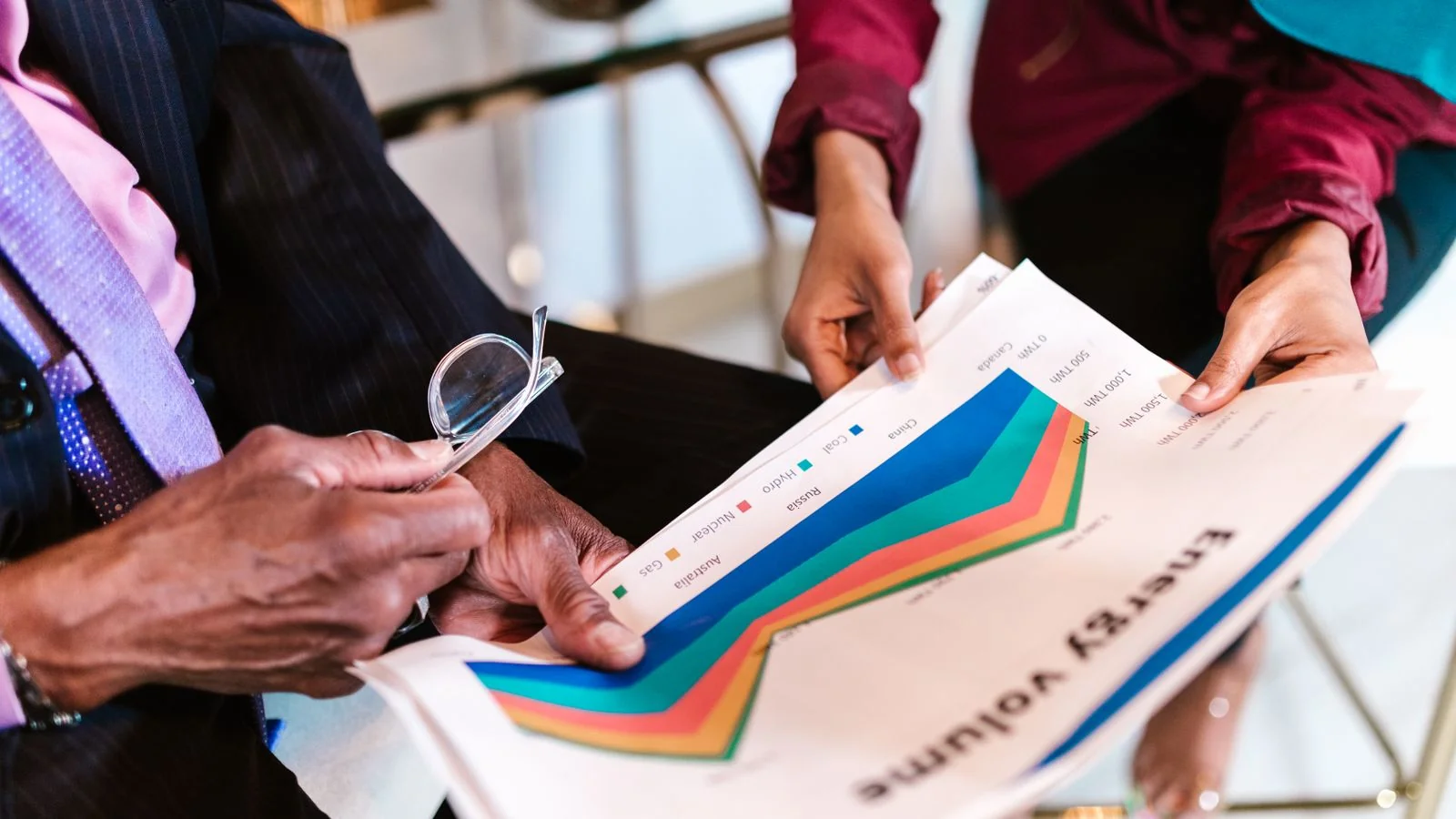 Two professionals reviewing detailed charts together at an office desk
