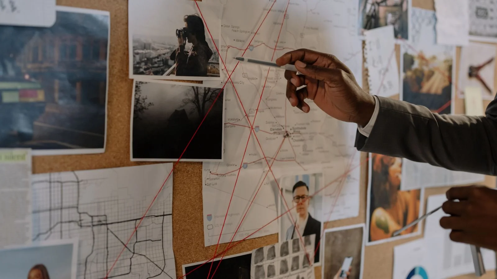 Investigator studying a corkboard of linked photos and maps, like Google mapping related entities